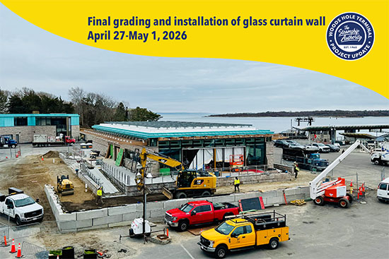 Construction site with workers and vehicles near a modern building by the water; sign indicates grading and glass wall installation in 2026.