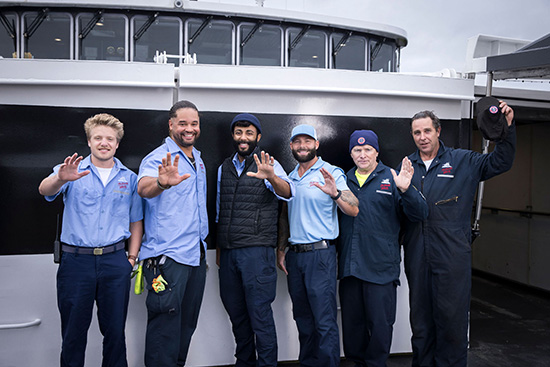 A group of men standing in front of a boat.